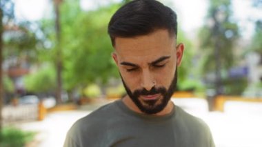 Şehir parkında sakallı yakışıklı, genç ve düşünceli bir adam.