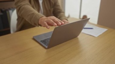 Ev ofisinde dizüstü bilgisayar kullanan odaklanmış bir adam üretkenliği ve modern uzaktan çalışma hayatını çağrıştırıyor..