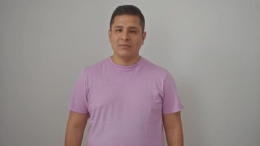 Kollarını kavuşturmuş genç İspanyol bir adam, mutlu bir gülücük saçıyor, izole edilmiş beyaz bir arkaplanda kendinden emin görünüyor.