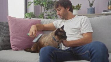 Genç bir adam evde dinleniyor. Kanepede siyam kedisini tımar ediyor. Huzurlu bir ev hayatı tasvir ediyor..