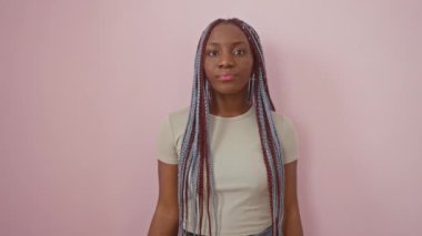 Güçlü Afro-Amerikalı kadın kollarını gösteriyor. Güç, güç ve zindelik içinde tek başına duruyor. Pembe izole edilmiş arka plana karşı kendine güveni yayıyor.