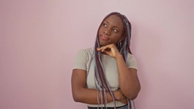 Düşünceli Afrikalı Amerikalı kadın, elleri çenesinde, kafa karıştırıcı cevap için soyutlanmış pembe arka plan