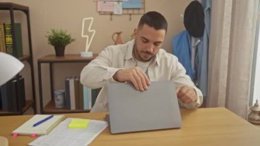 Modern bir ofis düzeninde dizüstü bilgisayar kullanan yakışıklı İspanyol bir adam, profesyonellik yayıyor ve odaklanıyor..