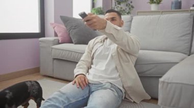 Genç bir İspanyol adam evinde köpeğiyle rahat bir oturma odasında rahatlıyor, evinin rahatlığının tadını çıkarıyor..