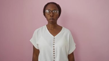 Genç Afro-Amerikan kadın gözlük takıyor, pembe arka planda komik ve çılgın bir jest için komik balık suratı yapıyor.