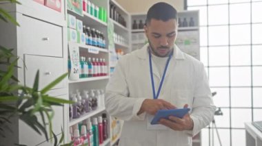 Laboratuvar önlüklü İspanyol eczacı modern eczanede kapalı yerde tablet kullanıyor.