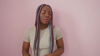 Kendine güvenen Afrikalı Amerikalı kadın, kollarını kavuşturmuş, elleri çenesinde, kameraya bakıyor. Gülümsüyor. Olumlu şeyler düşünüyorum. izole edilmiş pembe bir arkaplanda.