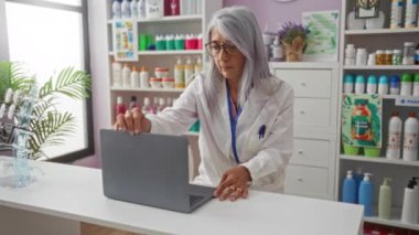 Eczanede dizüstü bilgisayarda çalışan kadınlar tıbbi ürünler ve kozmetiklerle çevrili.