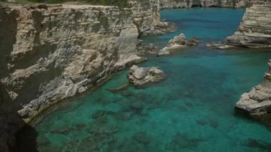Güzel güneşli bir günde, Torre Dell 'orso, Salento, Puglia, İtalya' daki berrak turkuaz sularının ve engebeli uçurumların çarpıcı manzarası.