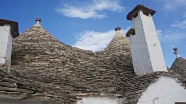 İtalya, Alberobello 'da geleneksel Trullo evi. Mavi gökyüzünün altında karakteristik taş çatı ve beyaz baca var.