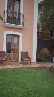 Güneşli villa bahçesi, yemyeşil ağaçlar, güneşli yataklar, çimenler ve rahatlama ve lüksü taşıyan ahşap banklar..
