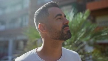 Yakışıklı İspanyol adam güneşli şehir parkında yukarı bakıyor, Flora şehrinin ortasında sakin ve düşünceli bir ruh hali sergiliyor..