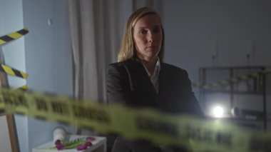 Suç mahallinde kararlı bir kadın dedektif. Dikkatli bir şekilde bantlanmış bir silahı hedef alıyor.