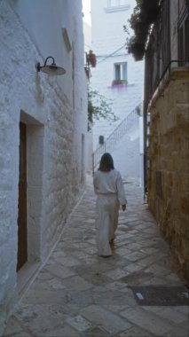 Genç bir kadın polignano 'nun büyüleyici taş caddelerinde yürüyor. Puglia, İtalya' da bir kısrak. Etrafı beyazlatılmış binalar ve kırsal mimariyle çevrili..