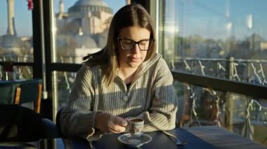 Düşünceli bir kadın İstanbul 'da bulanık hagia soo manzaralı bir restoranda geleneksel Türk kahvesinin tadını çıkarıyor..