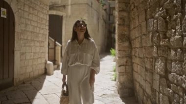 Genç bir İspanyol kadın, Bari, İtalya 'nın büyüleyici eski sokaklarını keşfediyor. Puglia' da. Güneş ışığıyla aydınlanan güzel, tarihi, taş mimarinin tadını çıkarıyor..