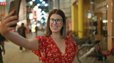 Osaka Caddesi 'nin ışıklarını alan gözlüklü güzel İspanyol bir kadının canlı gece selfisi.