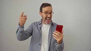 İspanyol orta yaşlı adam, izole edilmiş beyaz arka planda gülümseyen yüzüyle akıllı telefon kullanıyor.