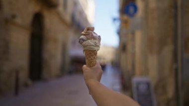 Genç bir kadın güneşli bir günde leziz bir dondurma külahı tutuyor Puglia, İtalya 'da tarihi bir kasaba, büyüleyici antik mimari, dükkanlar ve dar sokaklar ile çevrili..