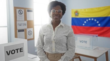 Seçim kolej odasında arka planda Venezuela bayrağıyla gülümseyen bir kadın, oy verme faaliyetlerini gösteriyor