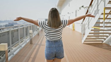 A brunette woman enjoys freedom while standing on the deck of a cruise ship overlooking the sea. clipart