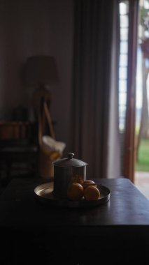 Koyu ahşap bir yüzey üzerinde antika bir kahve demliği ve taze portakallar içeren samimi bir ortam..