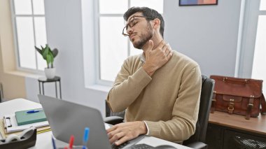 Ofisteki genç İspanyol bir adam boğazını tutarken rahatsızlık hissediyor. Ağrılı ya da acı verici bir his uyandırıyor..