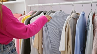 İspanyol kadın aydınlık bir kostüm odasında kıyafetlerini karıştırıyor..