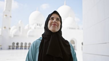 Abu Dabi 'nin Şeyh zayed camiinin önünde tesettür takan gülümseyen genç bir kadın kültürel turizm ve İslami mimariyi somutlaştırıyor..