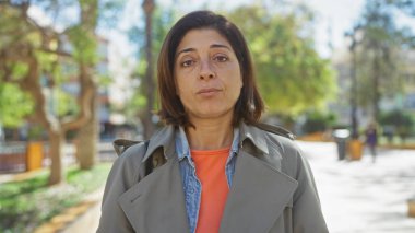 Ciddi bir ifadeyle gündüz vakti parkta dikilen olgun İspanyol kadın..