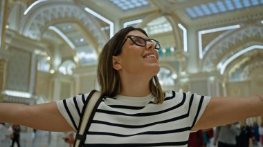 Kollarını açmış neşeli bir kadın Abu Dabi 'nin Qasr al Watan Sarayı' nın görkemine hayran. Kültür, seyahat ve mimariyi yansıtıyor..