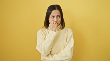 Genç bir İspanyol kadın, izole edilmiş sarı bir arka plana dalgın görünüyor..