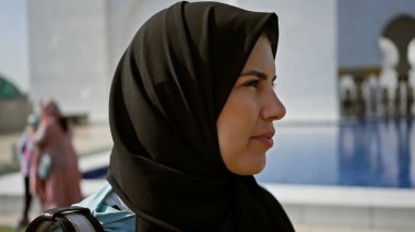 Abu Dabi 'deki İslami camide tesettürlü genç bir kadın düşünceli bir şekilde duruyor. Turizm ve kültürel keşifleri somutlaştırıyor..