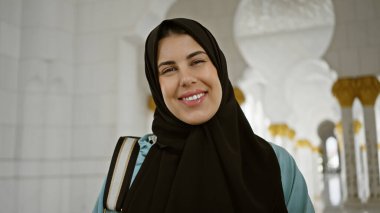 Süslü caminin içinde tesettürlü gülümseyen kadın Abu Dabi 'deki İslami kültürü ve mimari güzelliği temsil ediyor..