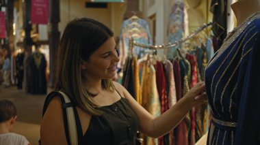 Genç bir kadın Dubai 'de bir çarşıda geleneksel giysileri inceliyor, Uae' de bir turist deneyimini canlandırıyor..