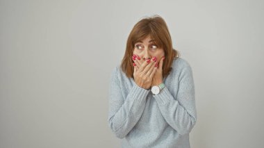 Şaşırmış olgun bir kadın, elleri izole edilmiş beyaz arka plana değdirerek ağzını kapatıyor.