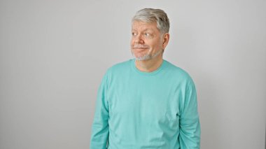 Gri saçlı, gri tişörtlü yaşlı bir adam izole edilmiş beyaz bir arka plana hafifçe gülümsüyor..
