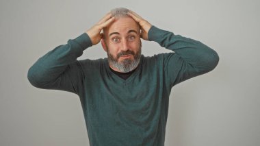 Kafası karışmış, sakallı beyaz bir adam, kafasını beyaz bir arka plana değdirip kafa karışıklığı ya da şaşkınlık yaratıyor..