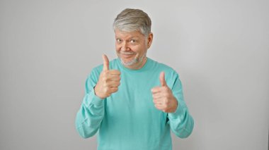 Beyaz bir arkaplan önünde gülümseyen kıdemli adam, pozitifliğini ve onayını ifade ediyor..