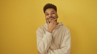 Yüzünde bej kapüşonlu gülümseyen Afrikalı genç bir adamın portresi.