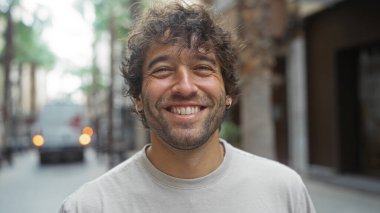 Şehir sokaklarında gülümseyen yakışıklı genç bir adam çekici özelliklerini ve tasasız tarzını gözler önüne seriyor.