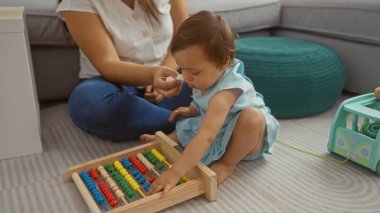 Mother and toddler daughter playing with a colorful abacus in a cozy living room, emphasizing family bonding and love indoors clipart