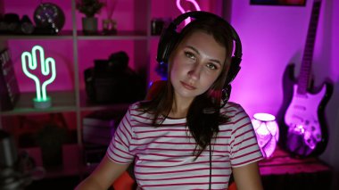 Neon ışıklı bir odada, çizgili gömlekli ve elektro gitarlı genç bir kadın, son moda, müzik temalı bir atmosfer öneriyor..