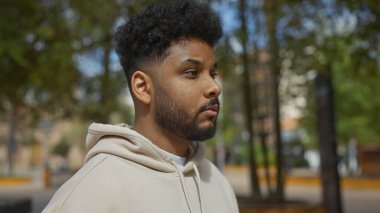 Parkta sakallı, kapüşonlu, düşünceli, yakışıklı bir adam..