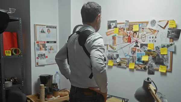 stock image Bearded man investigates crime board inside detective office, analyzing evidence and clues.