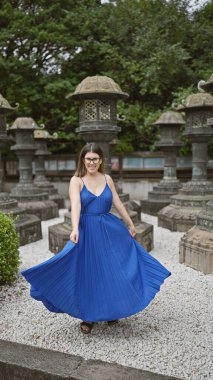 Gözlüklü güzel İspanyol kadın Tokyo, Ueno Park Tapınağı 'nda elbisesiyle sevinçle dönüyor. Canlı ruhu şehir ortamında dans ediyor, Japonya 'nın benzersizliğini yakalıyor..