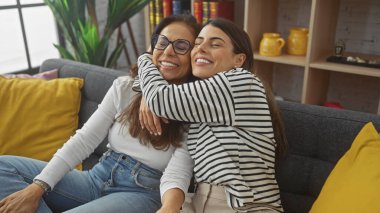 Keyifli bir anne ve kız evcil dekorun arasında sevgi ve aile bağını ifade ederek, rahat bir oturma odasında kucaklaşıyorlar..