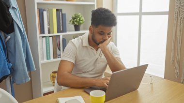 Modern ofis ortamında dizüstü bilgisayarla çalışan düşünceli bir Afrikalı Amerikalı..