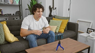 Modern bir apartman dairesinde oturan kıvırcık saçlı yakışıklı, genç, İspanyol bir adam..