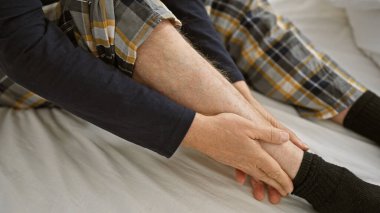 Yetişkin bir adam evde bacağını yatakta tutarak acı çekiyor..